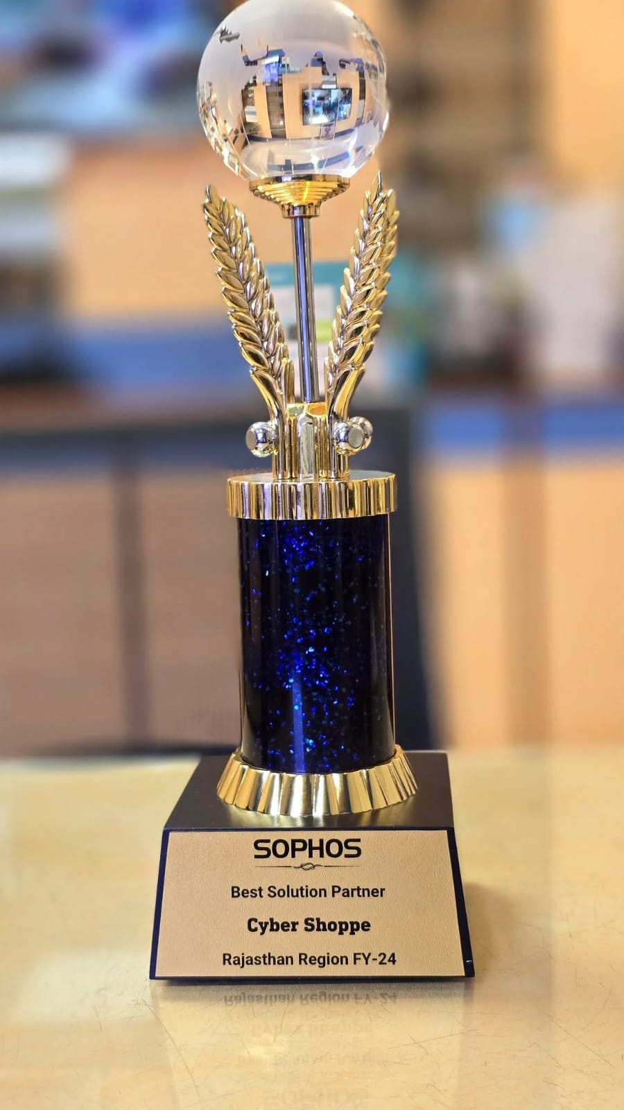 A crystal globe trophy on a blue and gold column, plaque reading "Sophos — Best Solution Partner — Cyber Shoppe — Rajasthan Region FY-24".