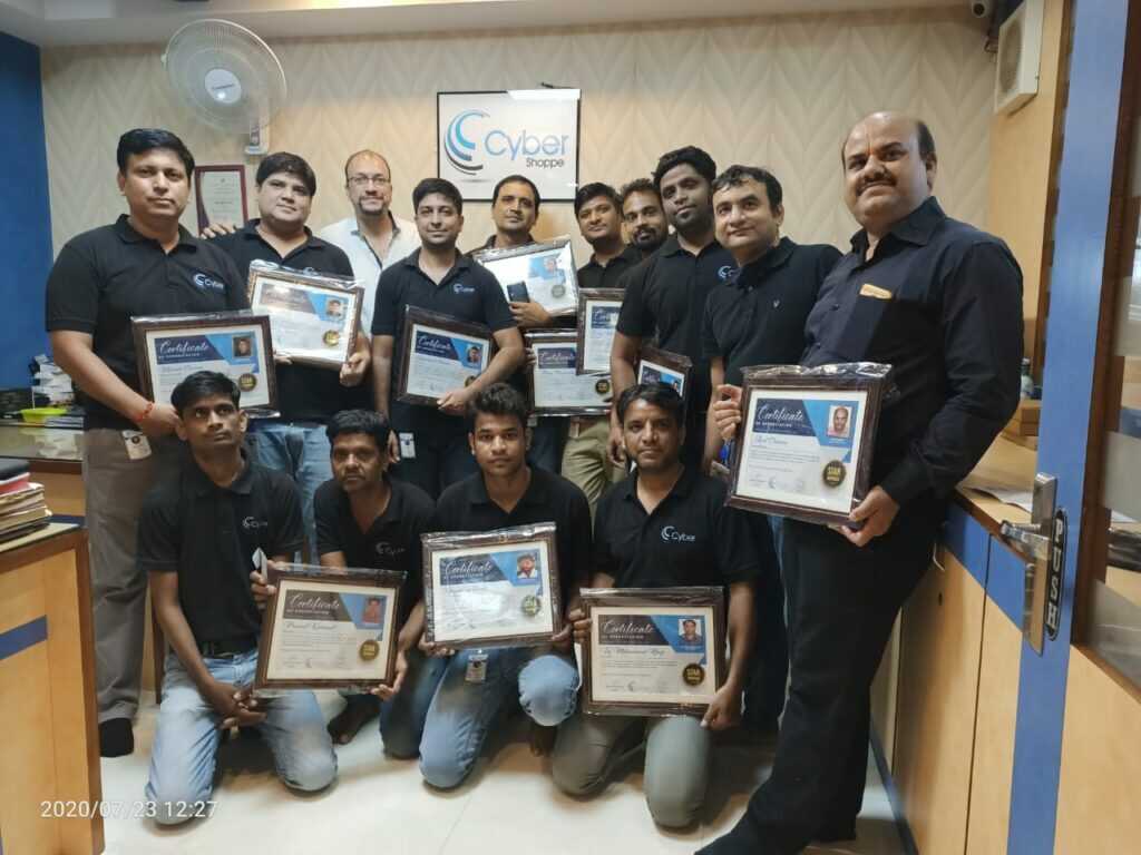 Engineers holding their framed vendor certification certificates at the Cyber Shoppe office in 2020.