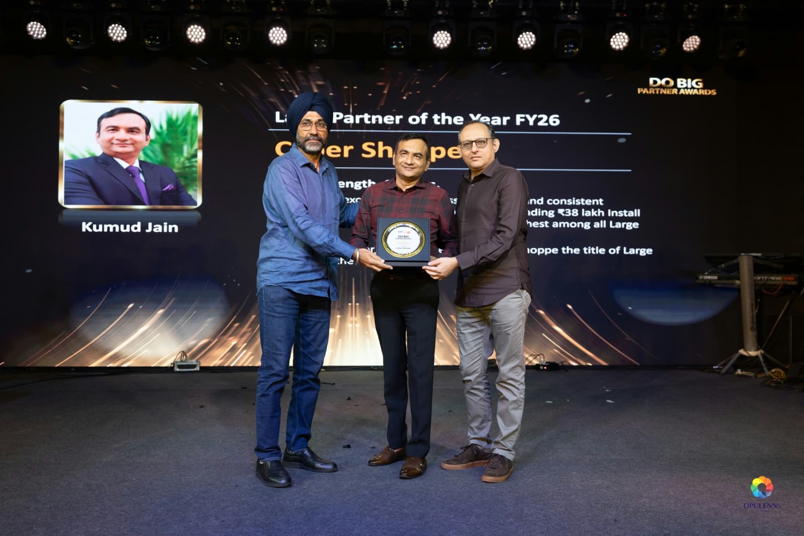 Cyber Shoppe receiving the Large Partner of the Year FY26 award on stage at the Tata Tele Business Services DO BIG Partner Awards, with co-founder Kumud Kumar Jain named on the screen behind.