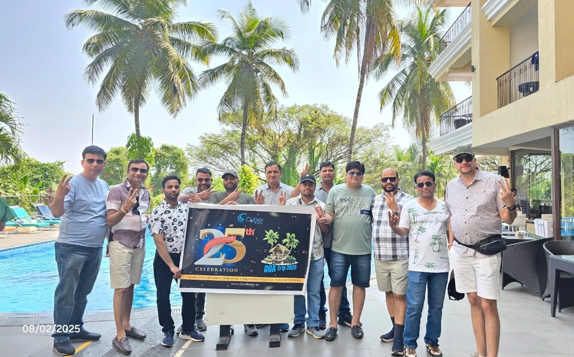 The Cyber Shoppe team gathered poolside in Goa holding a banner for the company's 25th anniversary celebration trip.